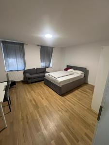 a bedroom with a bed and a couch and wooden floors at Ethical Choice Residence in Kaiserslautern