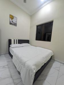 a white bedroom with a bed with a television at Shareen Homestay Morib in Banting
