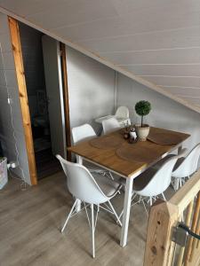 a dining room with a wooden table and white chairs at Bjarmaland in Vestmannaeyjar