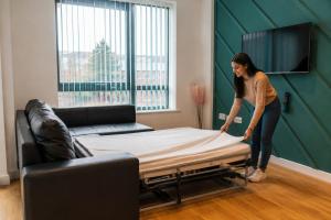 a woman is working on a bed in a room at Sidemersey Livings- Rare Accessible 2BR Liverpool City Centre Apartment in Liverpool