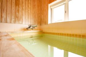 a bathroom with a tub with a window and a sink at べっどぷらす in Wakkanai