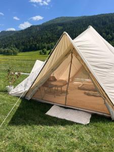 a tent with a table and a chair in a field at Wiesn Relax Camping Steiner in Ranten
