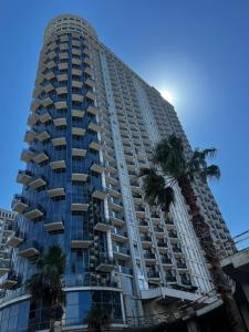 a tall building with palm trees in front of it at Luxury South Beach Hotel in Batumi
