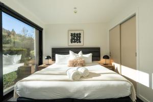 a bedroom with a large bed with towels on it at Hygge Garden Apartment with Private Sauna in Queenstown