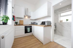 a white kitchen with white cabinets and a microwave at The Loft Apartment in Elland +13 photos