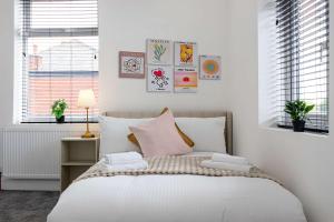 a bedroom with a bed with white sheets and pink pillows at The Loft Apartment in Elland