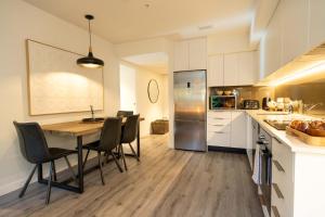a kitchen with a table and chairs and a refrigerator at Hygge Garden Apartment with Private Sauna in Queenstown +15 photos