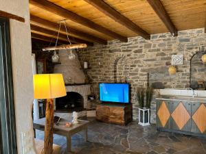 a living room with a tv and a stone wall at Paros Poolside Cozy Nests - Summer & Salty Getaways in Kalami
