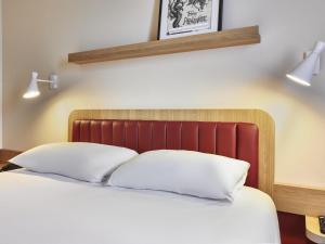 a bedroom with a bed with two pillows at ibis Styles La Roche-sur-Yon in Mouilleron-le-Captif