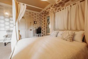 ein Schlafzimmer mit einem großen weißen Bett und Vorhängen in der Unterkunft Old Orleton Inn - Telford in Telford
