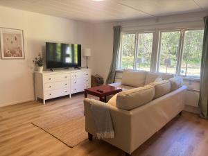 a living room with a white couch and a flat screen tv at Stuga Rödhake in Annerstad