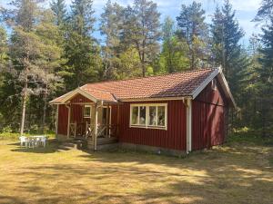 a red tiny house in a yard with trees at Stuga Rödhake in Annerstad