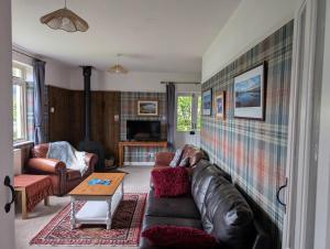 a living room with a leather couch and a table at Callart View in Ballachulish