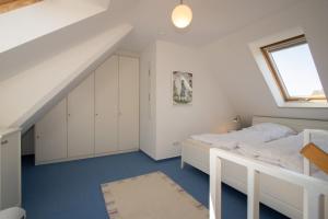 a white bedroom with a bed and a window at Ferienwohnung Filter in Hörnum