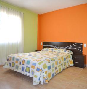 a bedroom with a large bed with an orange wall at Apartamento Goya in Málaga
