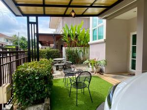 a patio with a table and chairs on the grass at J&Y Happy Home in Ban Rong