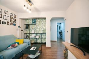 a living room with a blue couch and a television at The Clock Tower Apartment in Jaén