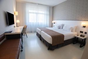 a hotel room with a large bed and a desk at Hotel Ilunion Bilbao in Bilbao