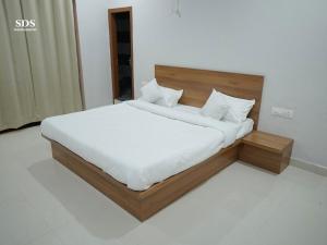 a bed with a wooden headboard and white sheets at Hotel Chandra Hari Palace in Sānchor +3 photos