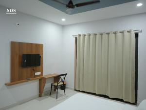 a room with a curtain and a desk and a television at Hotel Chandra Hari Palace in Sānchor