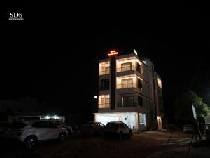 a tall building with cars parked in front of it at night at Hotel Chandra Hari Palace in Sānchor