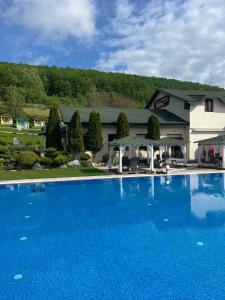 a large blue swimming pool in front of a building at Pensiunea Eden in Jibou