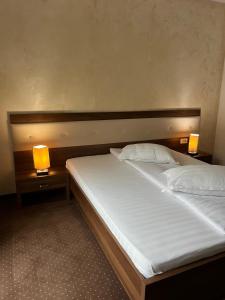 a bedroom with a bed with two lamps on it at Pensiunea Eden in Jibou