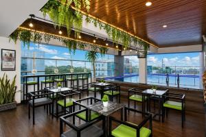 a restaurant with tables and chairs and a pool at Whiz Prime Hotel Basuki Rahmat Malang in Malang