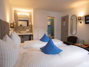 a hotel room with two beds with blue pillows at Hotel-Restaurant Bellevue in Flims