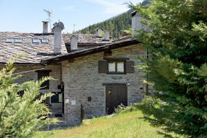 an old stone house with a door in a field at La Tana con l'Ermellino in Morgex
