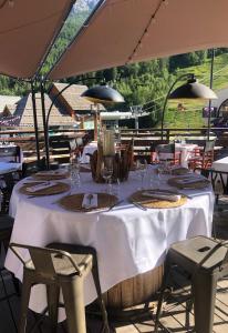 a table with a white table cloth and chairs and an umbrella at Grand Hôtel & Spa NUXE Serre Chevalier in Saint-Chaffrey +71 photos