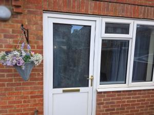 Eine weiße Tür mit einem Blumenkorb neben einem Fenster in der Unterkunft Reading Studio Flat in Caversham