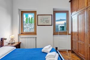 a bedroom with a blue bed and two windows at Villa Porlezza Lake view in Cima