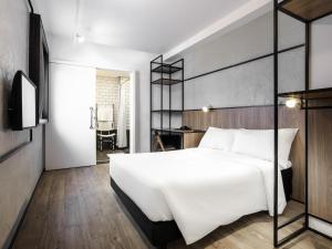 a bedroom with a large white bed and a desk at ibis Botucatu in Botucatu