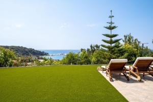 two chairs and a christmas tree on a lawn at Icarus Luxury Beachfront Villa in Gialiskari