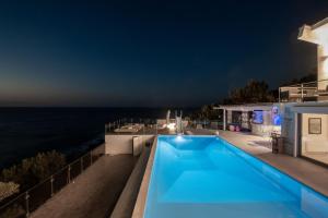 a house with a swimming pool at night at Icarus Luxury Beachfront Villa in Gialiskari +70 photos