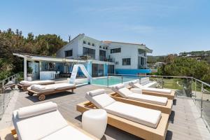 a patio with chaise lounge chairs and a swimming pool at Icarus Luxury Beachfront Villa in Gialiskari
