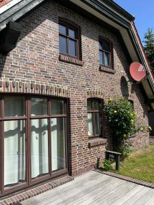 a brick house with large windows on it at Ferienhaus am Badesee 4 in Aurich +11 photos