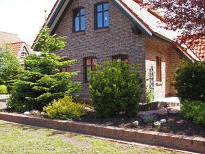 a brick house with bushes in the front yard at Ferienhaus am Badesee 4 in Aurich