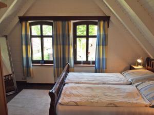 a bedroom with two beds and two windows at Ferienhaus am Badesee 4 in Aurich