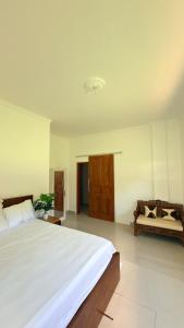 a bedroom with a large white bed and a couch at Hideaway in Amed