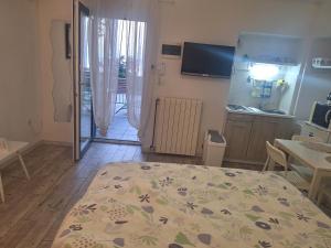 a bedroom with a bed and a kitchen with a television at Studio Laura in Ičići