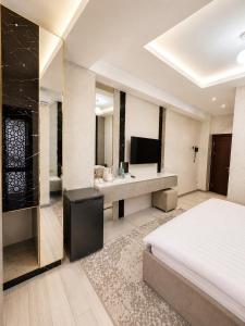 a bedroom with a bed and a television and a bathroom at Firdavsi Hotel in Dushanbe