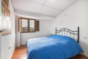 a bedroom with a blue bed in a white room at El Corralon de Severo in Hinojales