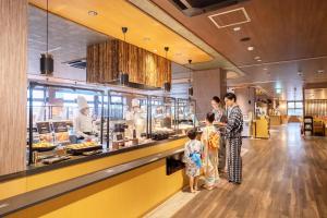 a group of people standing at a counter in a restaurant at Ooedo Onsen Monogatari Premium Hotel Fugetsu in Beppu