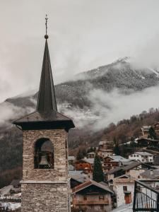 a clock tower with a steeple on top of a city at Hôtel Le Monal in Sainte-Foy-Tarentaise