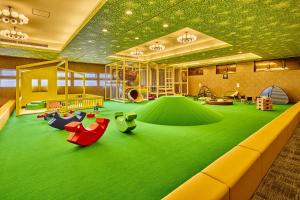 a childrens play room with green carpet and furniture at Ooedo Onsen Monogatari Premium Hotel Fugetsu in Beppu