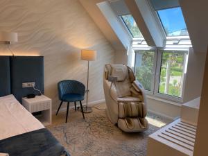 a bedroom with a chair and a bed and windows at Duna Corner Panzió in Kismaros