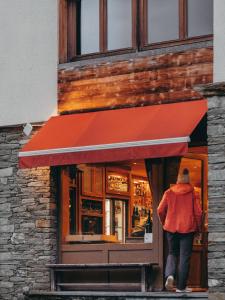 a person walking into a store with a red awning at Hôtel Le Monal in Sainte-Foy-Tarentaise