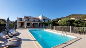 a swimming pool with chairs and umbrellas in front of a house at Casa Nova - Chambres d'hôtes en Corse in Sagone